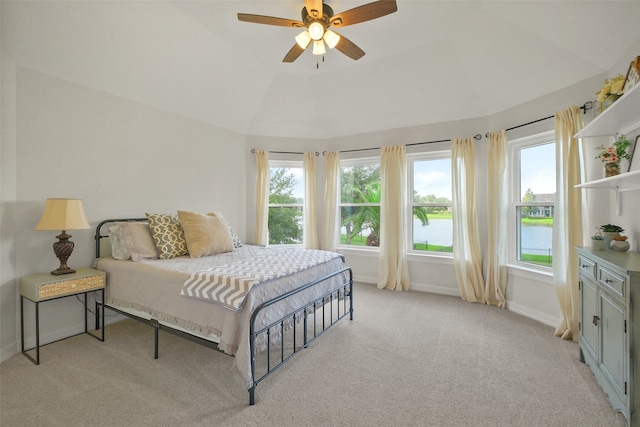 carpeted bedroom with a water view, vaulted ceiling, and ceiling fan