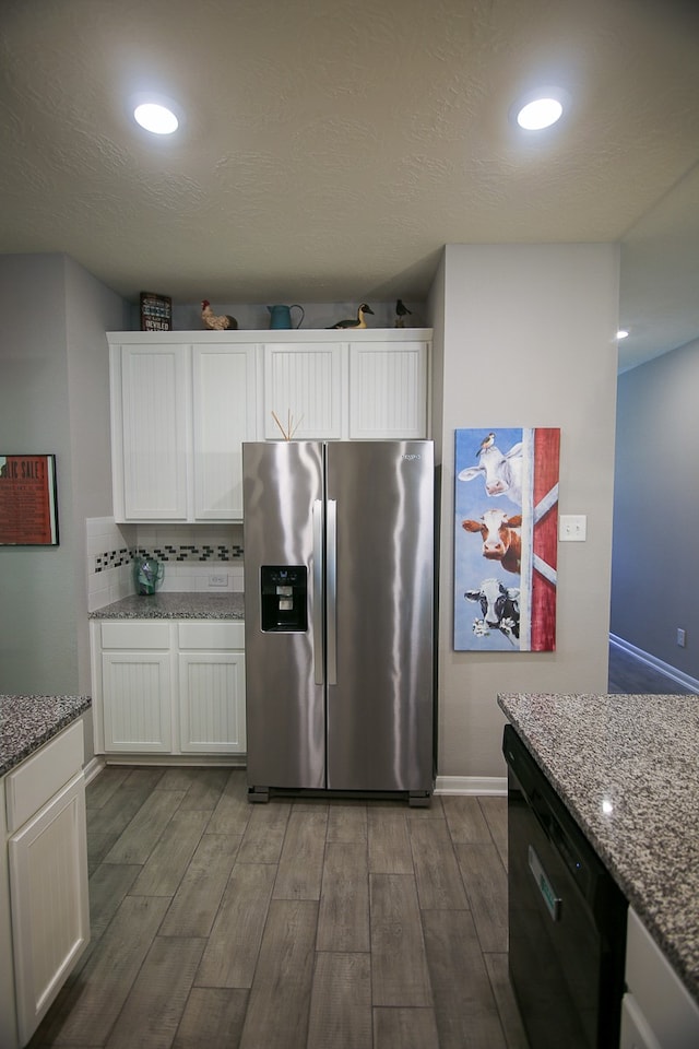 kitchen featuring white cabinets, stainless steel fridge with ice dispenser, hardwood / wood-style flooring, black dishwasher, and light stone countertops