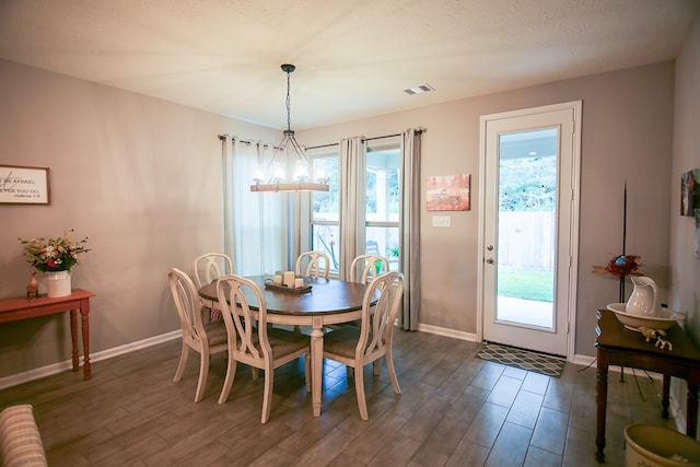 dining space featuring dark wood-type flooring and a notable chandelier