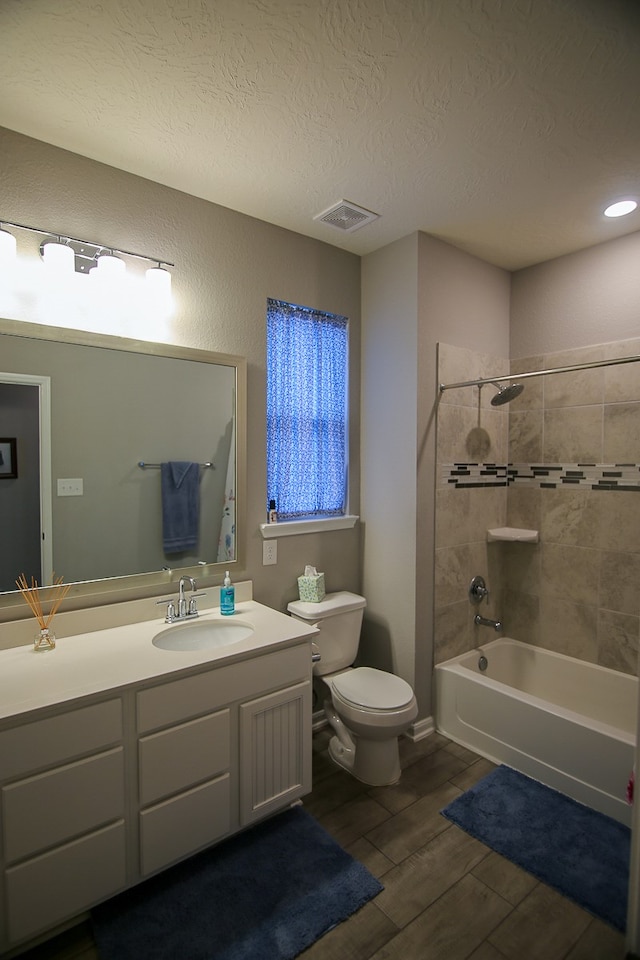 full bathroom featuring vanity, a textured ceiling, toilet, hardwood / wood-style floors, and tiled shower / bath