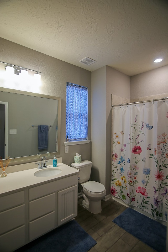 bathroom featuring vanity, wood-type flooring, a textured ceiling, a shower with curtain, and toilet