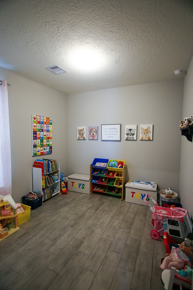 playroom with a textured ceiling and wood-type flooring