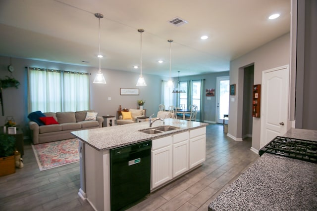 kitchen featuring an island with sink, sink, decorative light fixtures, white cabinetry, and black dishwasher