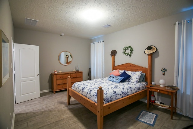 bedroom with a textured ceiling and hardwood / wood-style flooring