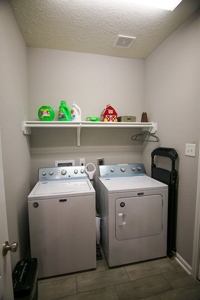 clothes washing area featuring washer and clothes dryer, a textured ceiling, and dark hardwood / wood-style floors