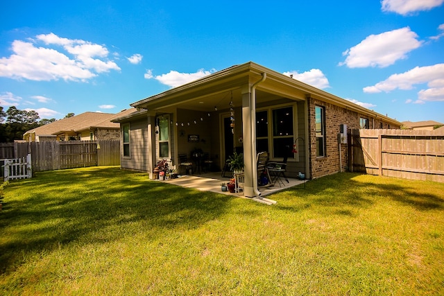 rear view of house with a patio and a yard