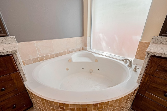 bathroom featuring vanity and tiled tub