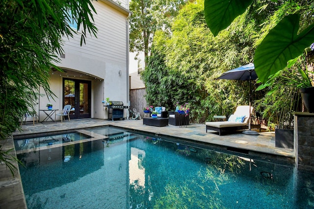 view of pool featuring a patio, a pool with connected hot tub, outdoor lounge area, grilling area, and french doors