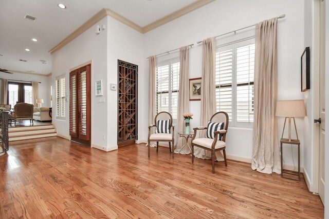 living area with light hardwood / wood-style flooring, plenty of natural light, and crown molding