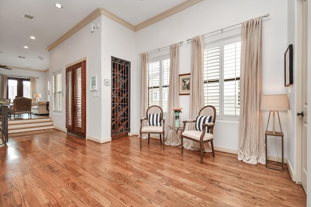 living area featuring ornamental molding, visible vents, baseboards, and light wood-type flooring