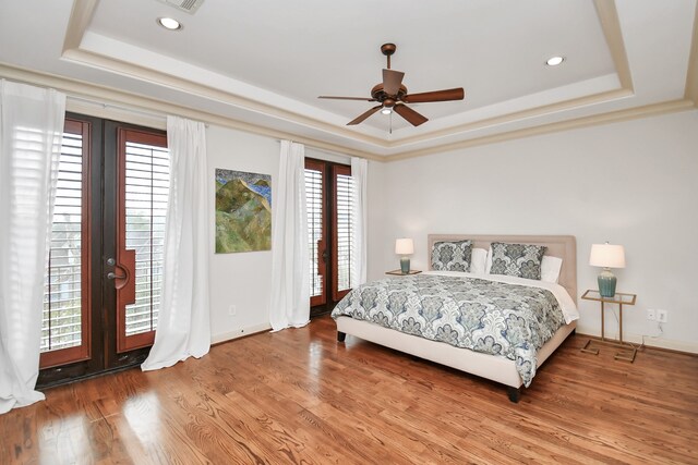 bedroom with multiple windows, hardwood / wood-style flooring, and a raised ceiling