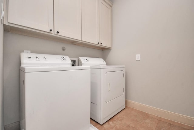 washroom featuring separate washer and dryer, cabinet space, and baseboards