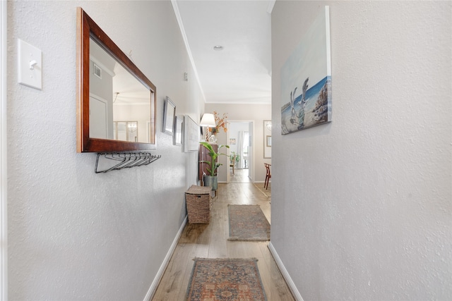 hall with light wood-type flooring and crown molding