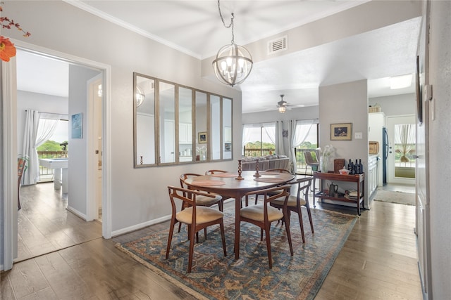 dining space featuring hardwood / wood-style flooring, ceiling fan with notable chandelier, and crown molding