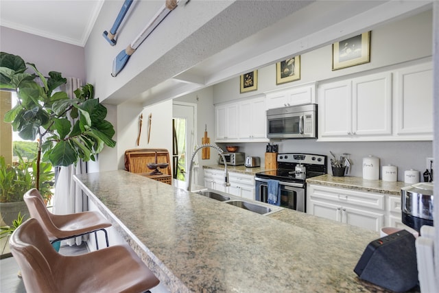 kitchen featuring appliances with stainless steel finishes, crown molding, a breakfast bar, and white cabinets