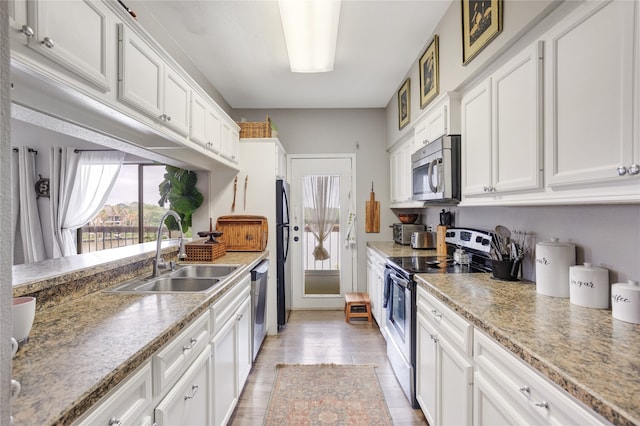 kitchen with light hardwood / wood-style floors, appliances with stainless steel finishes, sink, and white cabinetry