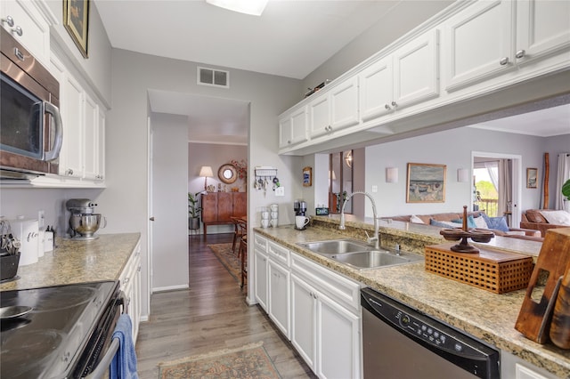 kitchen with white cabinetry, appliances with stainless steel finishes, hardwood / wood-style floors, and sink