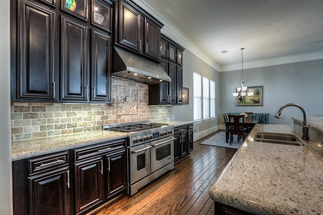 kitchen with light stone counters, dark wood-type flooring, sink, pendant lighting, and range with two ovens