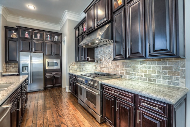 kitchen featuring appliances with stainless steel finishes, dark hardwood / wood-style flooring, extractor fan, and backsplash