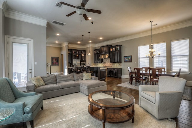 living room featuring light hardwood / wood-style floors, ceiling fan with notable chandelier, and ornamental molding