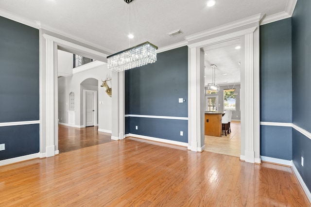 unfurnished room with hardwood / wood-style flooring, ornamental molding, and a chandelier