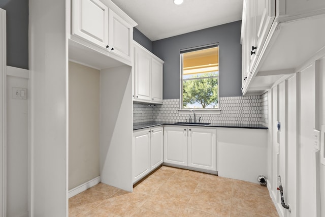 kitchen with backsplash, white cabinetry, sink, and light tile patterned flooring