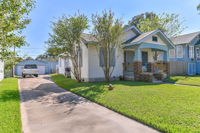 bungalow-style home featuring concrete driveway, an outdoor structure, a detached garage, a porch, and a front yard