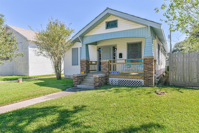 view of front of property with brick siding, fence, a front yard, and covered porch