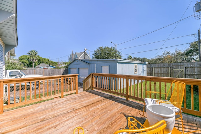 wooden terrace with a detached garage, an outbuilding, and a fenced backyard