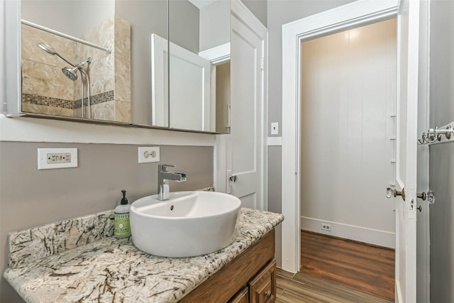 bathroom with a tile shower, hardwood / wood-style floors, and vanity