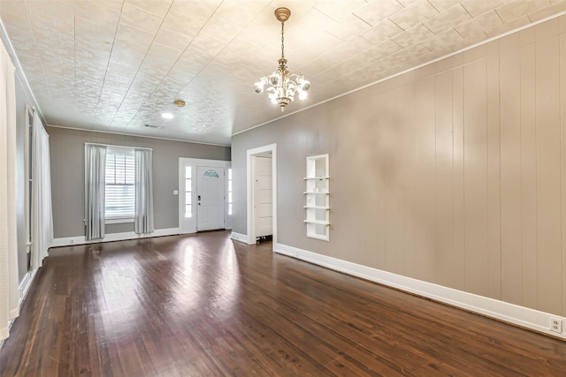 unfurnished living room with a chandelier, baseboards, crown molding, and dark wood-type flooring