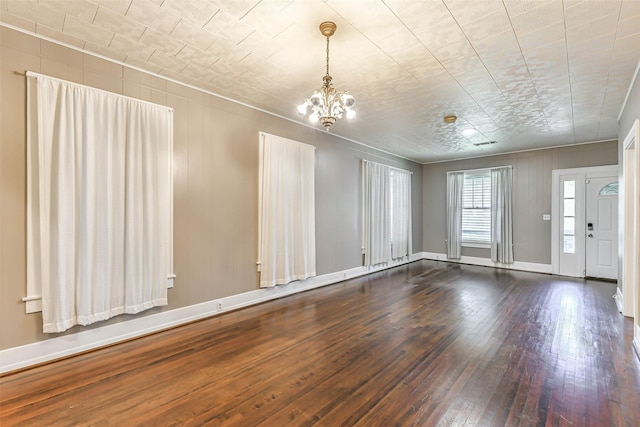 interior space featuring baseboards, an inviting chandelier, dark wood-type flooring, and ornamental molding