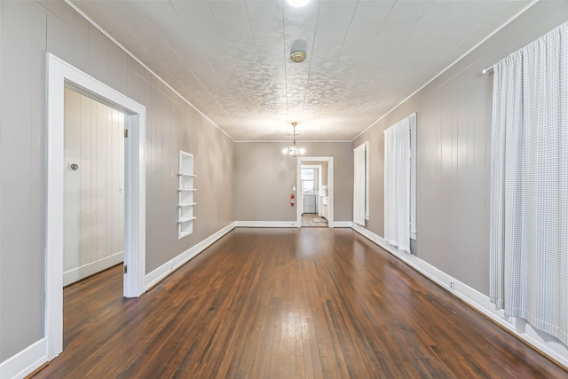 empty room featuring a notable chandelier and dark wood-type flooring