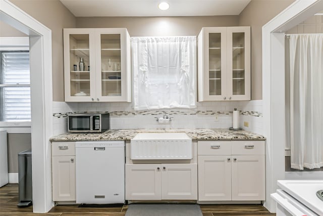 kitchen with light stone counters, white cabinets, white dishwasher, and sink