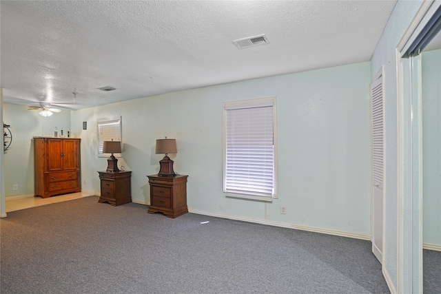 carpeted bedroom featuring ceiling fan, a textured ceiling, and a closet