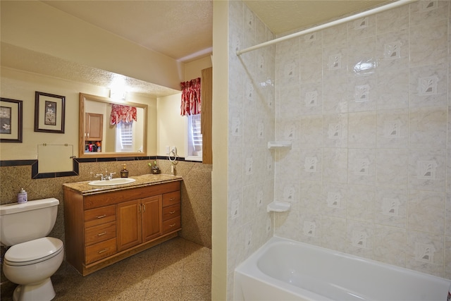 full bathroom featuring tile walls, vanity, toilet, and tiled shower / bath combo