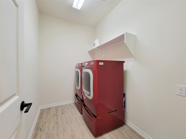 laundry area with light hardwood / wood-style flooring and washer and dryer