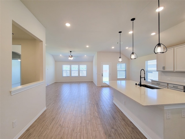 kitchen featuring pendant lighting, a large island with sink, sink, light hardwood / wood-style flooring, and ceiling fan