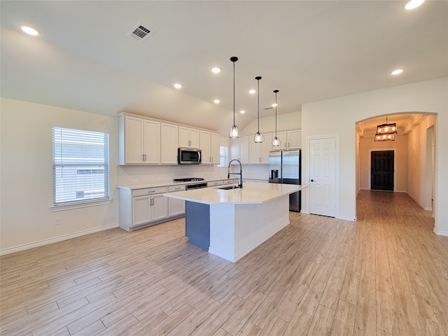 kitchen with stainless steel appliances, white cabinets, a center island with sink, and sink