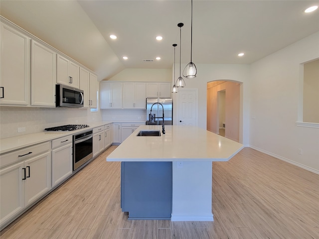 kitchen featuring an island with sink, white cabinets, vaulted ceiling, and appliances with stainless steel finishes