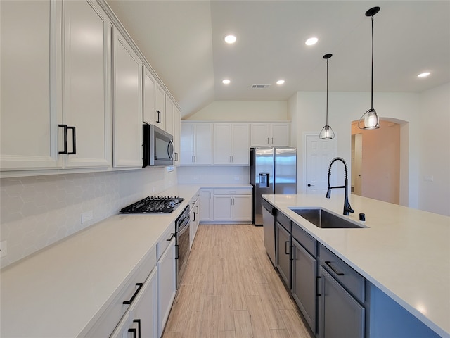 kitchen featuring white cabinets, pendant lighting, lofted ceiling, sink, and stainless steel appliances