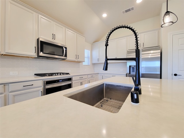 kitchen featuring white cabinets, pendant lighting, lofted ceiling, tasteful backsplash, and stainless steel appliances