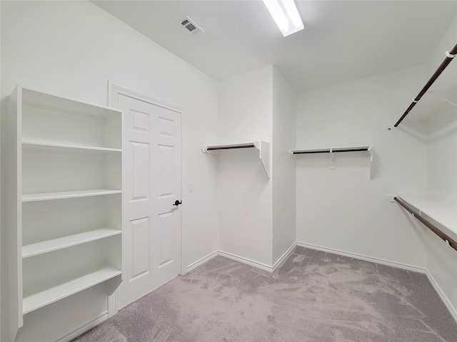 walk in closet with light carpet