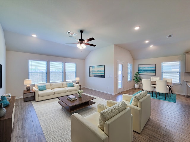 living room featuring ceiling fan, lofted ceiling, light wood-type flooring, and a wealth of natural light