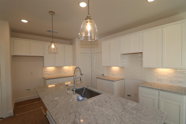 kitchen with a kitchen island with sink, sink, and white cabinets