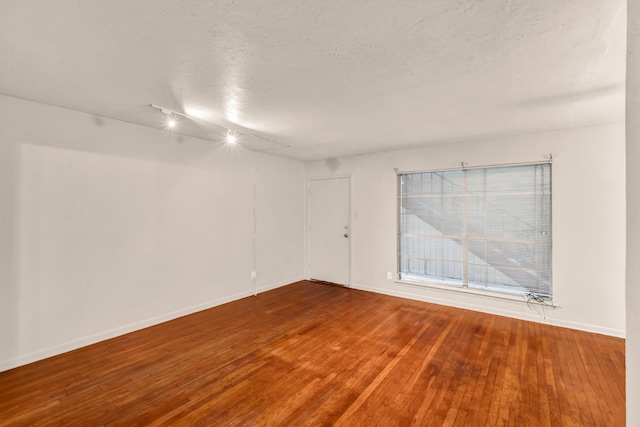 unfurnished room with wood-type flooring and a textured ceiling