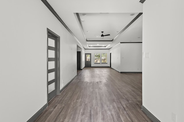 interior space with ornamental molding, ceiling fan, a raised ceiling, and dark hardwood / wood-style flooring