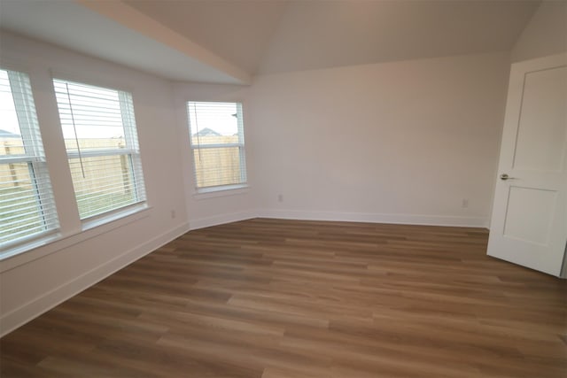 spare room with dark wood-type flooring and vaulted ceiling