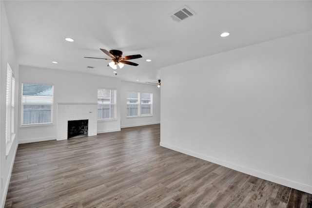 unfurnished living room with ceiling fan, a brick fireplace, and wood-type flooring