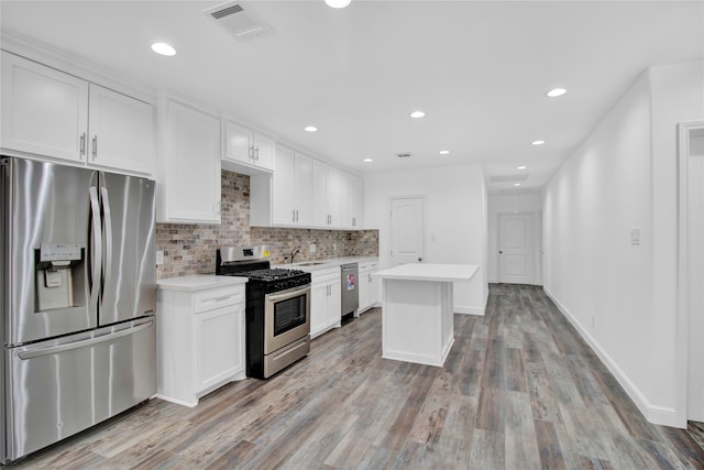 kitchen featuring light wood-type flooring, sink, white cabinets, a kitchen island, and stainless steel appliances